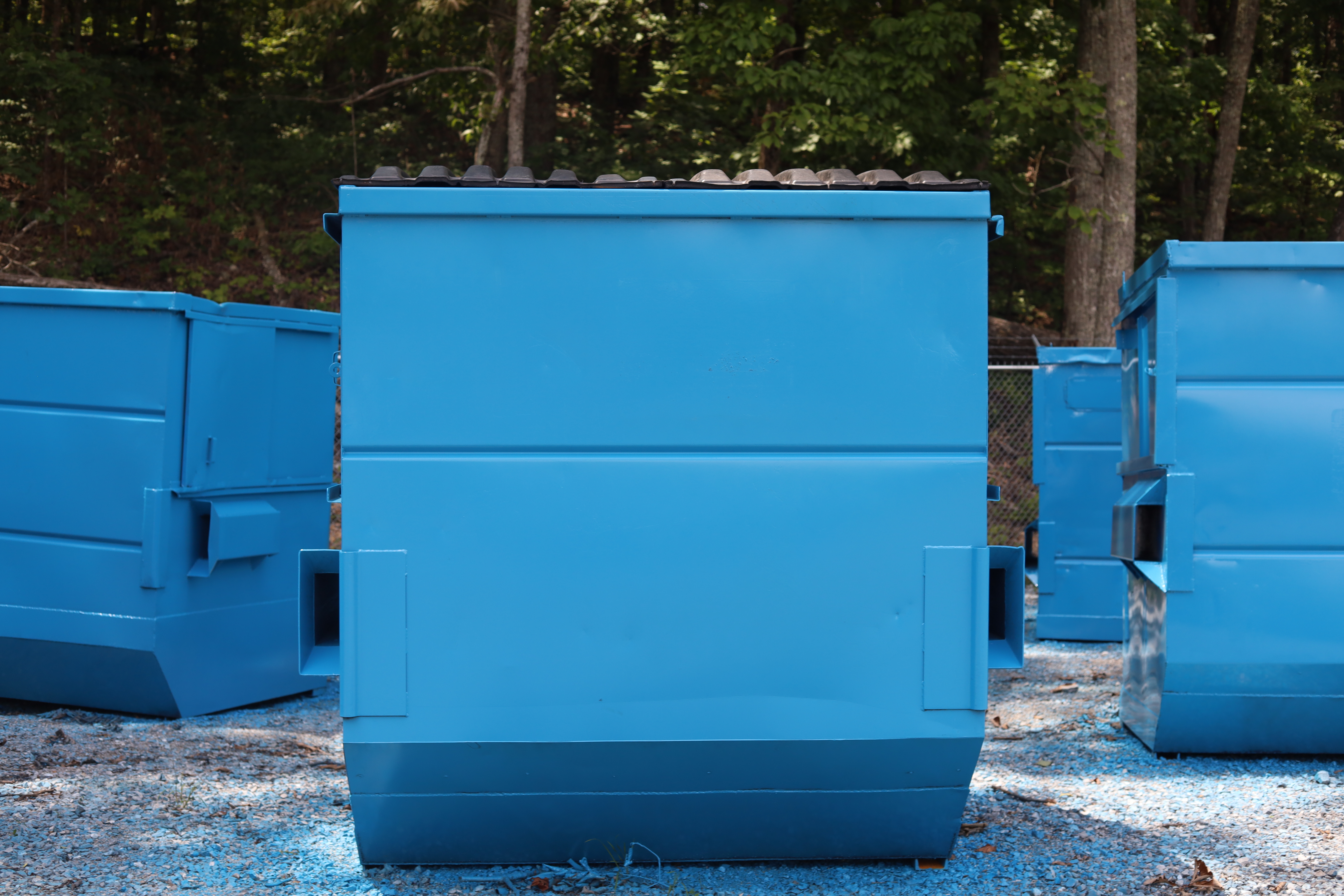Freshly repainted blue Trident front-load dumpsters after reconditioning